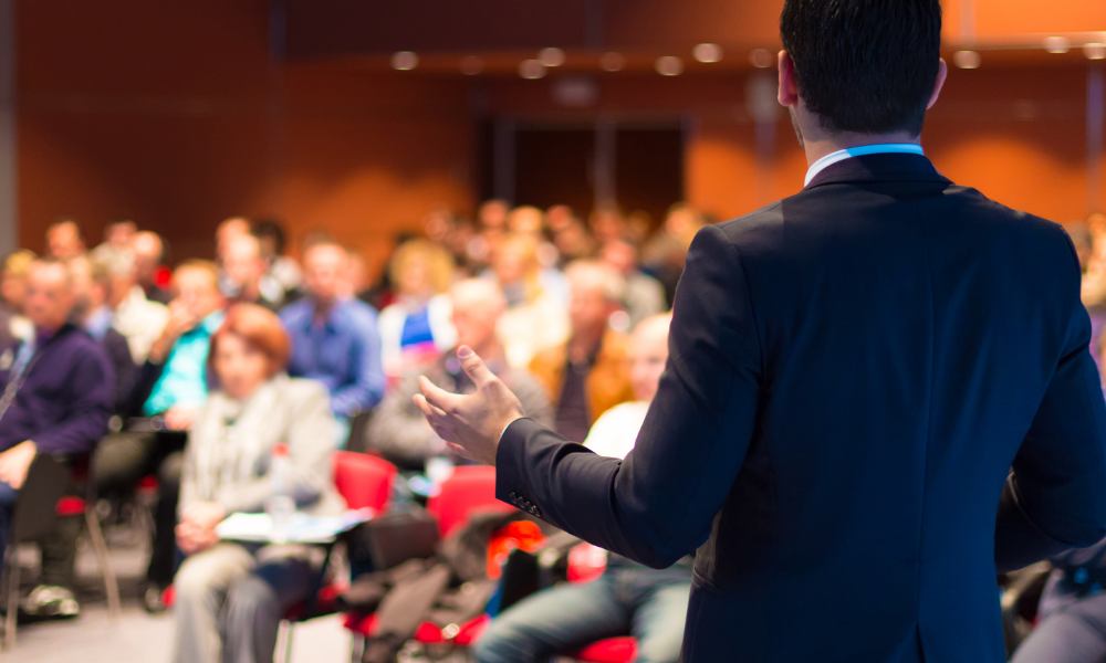 A speaker talking to an audience in an auditorium.