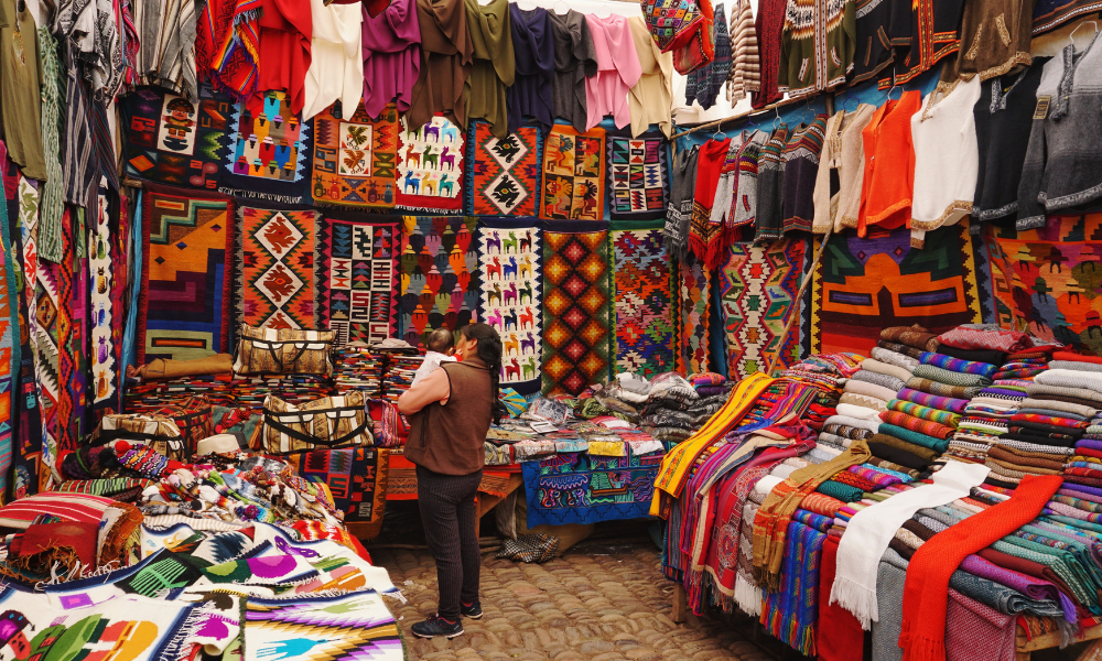A woman in a store with assorted fabrics and patterns.