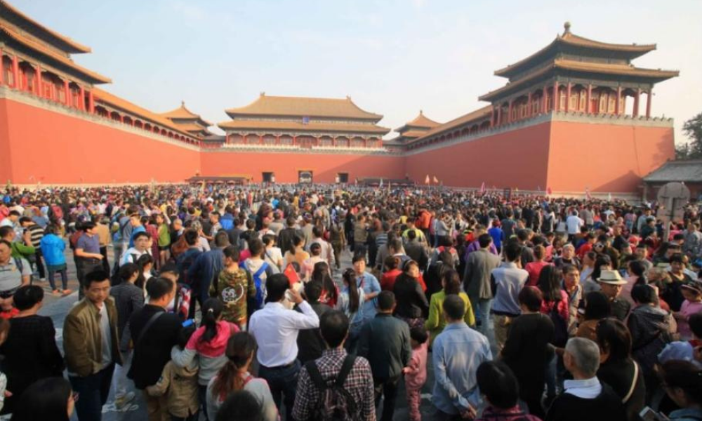 large crowd of tourists standing in front of ancient red building