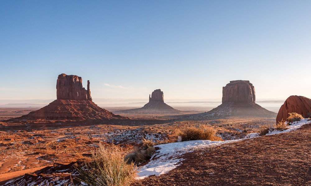 Wide angle overlook panoramic view of buttes and horizon in Monument Valley in Navajo Nation at sunrise colorful light.