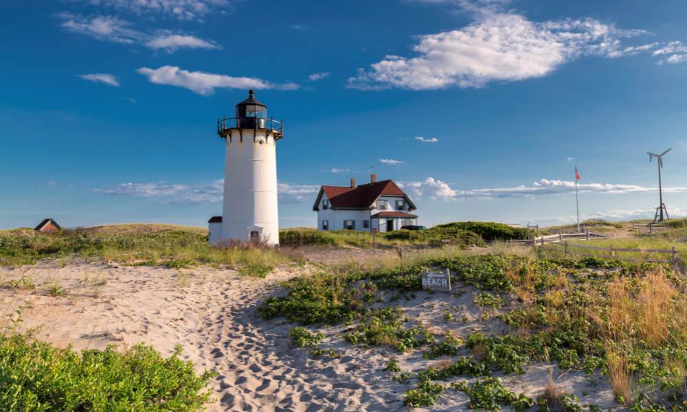 A Cape Cod ligthouse on top of grassy sand dune