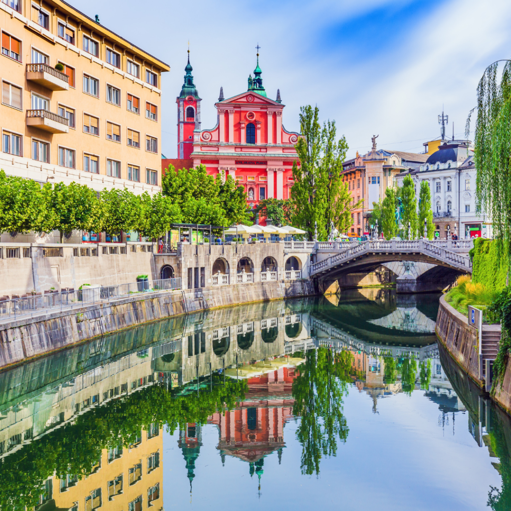 view of canal in Slovenia with brightly colored European buildings past a small bridge