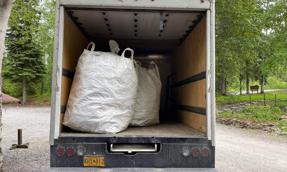 large white sacks of recycling in the back of a box truck.