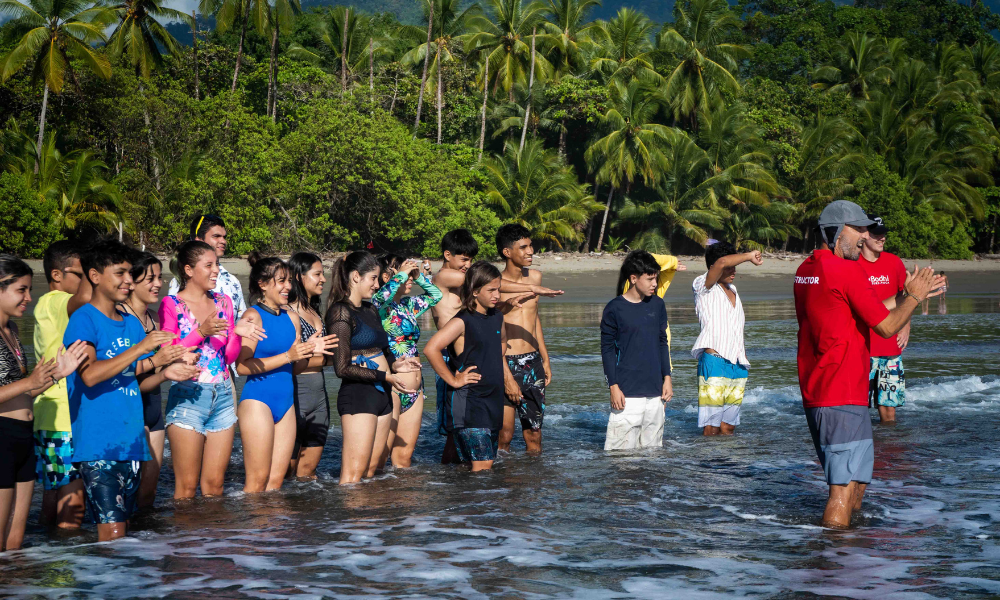 a group of students standing on the ocean watching something in the distance.