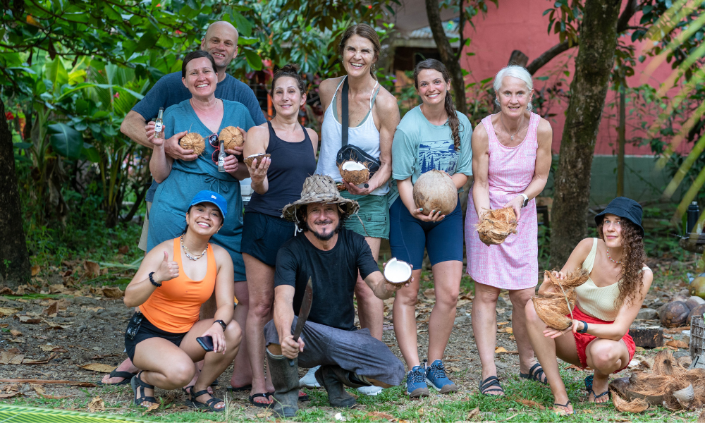 group of people holding coconuts smiling in tropical setting